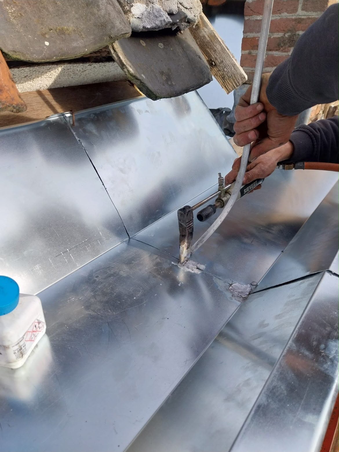 Vakman soldeert een waterdichte aansluiting in zink